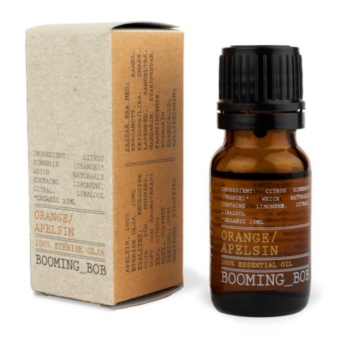 En liten brun eterisk oljeblaska märkt Orange/Apelsin och Boomning_Bob, bredvid en beige box med produktdetaljer.