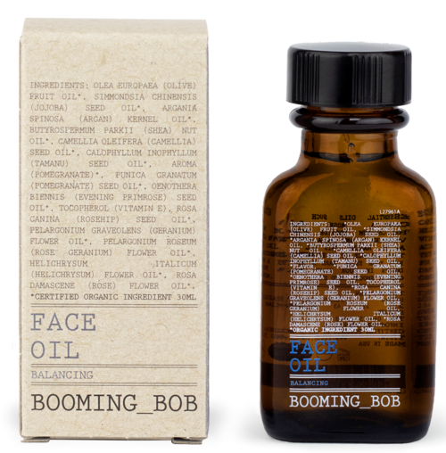 En brun glasflaska märkt 'Face Oil' med en blå och vit etikett, och en beige box med ingredienslista.