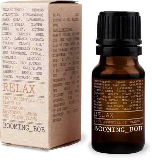 En liten bägare i bärnstensfärg med svart lock, märkt 'Relax BOOMING BOB', och en matchande box med ingredienslista för essentiella oljor.