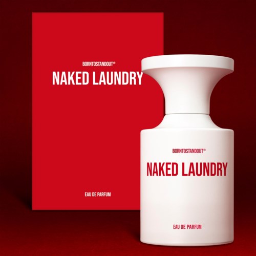 Valkoinen hajustepullo ja punainen laatikko, jossa lukee 'NAKED LAUNDRY', taustalla punainen.