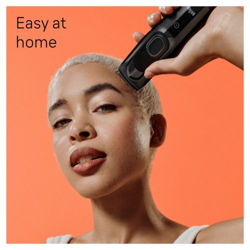 Een vrouw gebruikt een haarföhn op haar hoofd met een oranje achtergrond, en de woorden "Easy at home" staan linksboven.