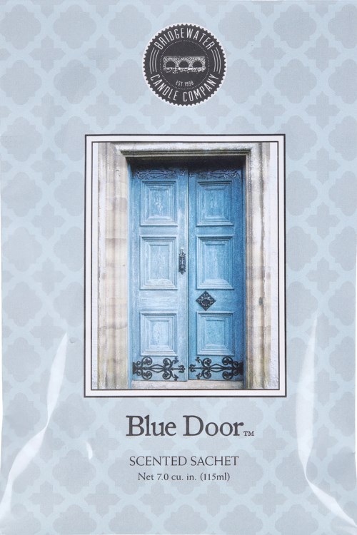 En blå dörr på en vägg, med en rund logga ovanför och text nedanför. Etiketten säger "Blue Door" och nämner en doftpåse.