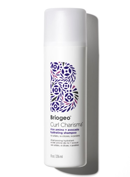 Eine weiße Flasche Shampoo mit einem lilafarbenen Blumenlogo, genannt Briogeo Curl Charisma, und erwähnt feuchtigkeitsspendend mit Reis Amino und Avocado.