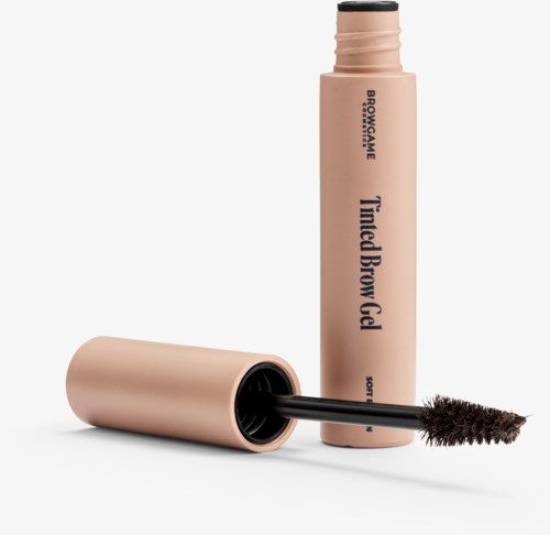 Ein beigefarbener Behälter mit Brauen-Gel, schwarzem Applikator und Bürste, beschriftet "Tamed Brow Gel".