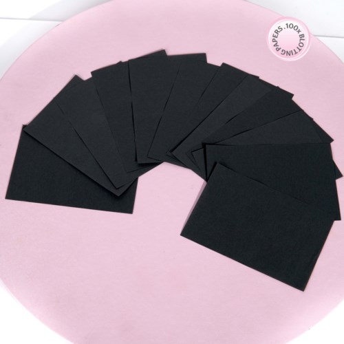 Flera små svarta kort är staplade i en fansform på en rosa yta.