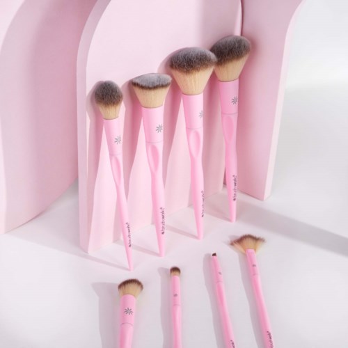 Samling rosa makeupborstar på en rosa och vit bakgrund, varierande i storlek och form.