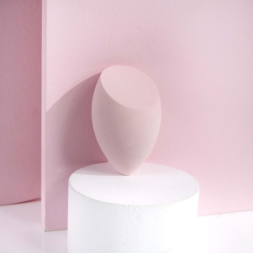 En slät, ovalformad skulptur på en vit rund plattform med rosa bakgrundsdelar.