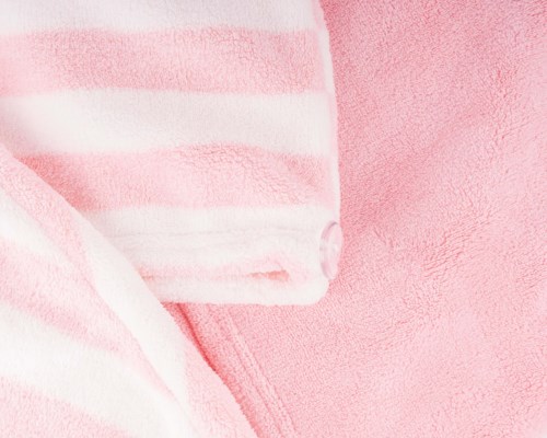 Close-up of pink and white striped fabric and a pink textured surface.