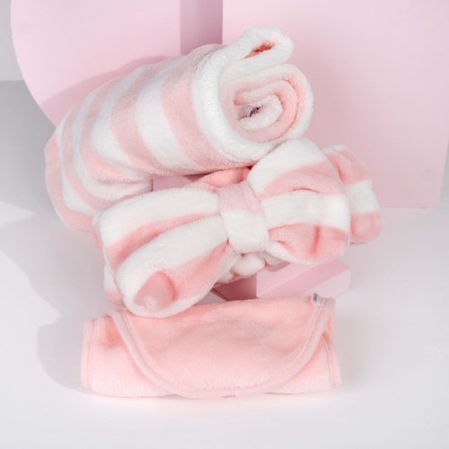 Mjuk rosa och vita randiga handdukar och ett matchande rosett-tillbehör, utställt mot en rosa bakgrund.