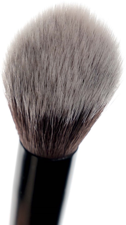 En makeupborste med täta, mjuka borst och svart skaft, används för att applicera puder eller rouge.