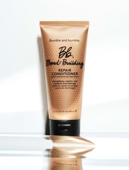 Bumble and bumble Repair Conditioner-rør står oppreist på flat overflate med litt produkt utspent ved siden av.
