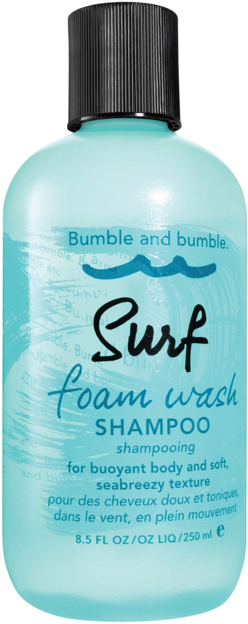 En flaska Bumble and bumble Surf skumtvättschampo, ljusblå med svart lock och vågiga textdesign.