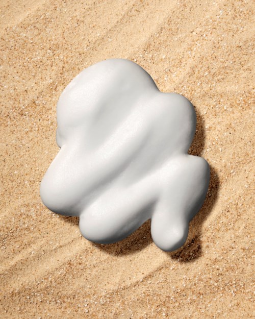 A white object with soft, rounded edges lies on sandy ground, resembling a cloud or blob.