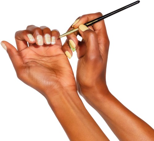A person with long nails is holding a makeup brush and applying nail polish or design on their nails.