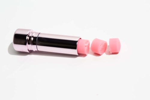 En läppstiftsrör med rosa suddpapper framför på en vit bakgrund.