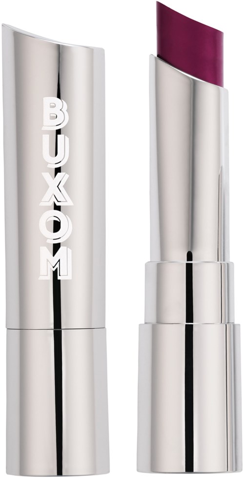 A silver lipstick tube with purple lipstick inside, standing upright next to its cap with the brand name 'BUXOM' on it.