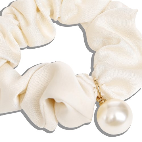 En cremefärgad tygscrunchie med ett stort pärl charms.