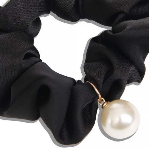 En sort stofscrunchie holder en stor hvid perlevedhæng, hvilket skaber et stilfuldt smykke.