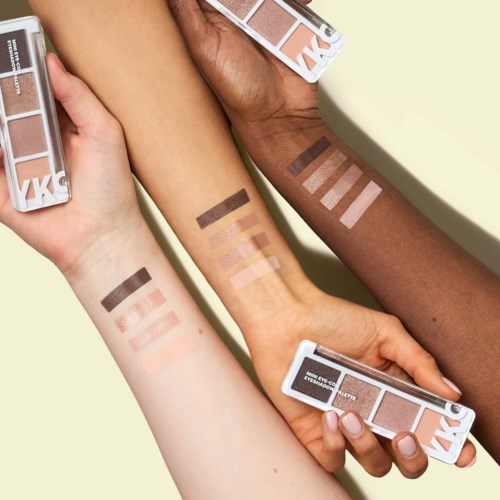 Tre arme viser forskellige hudtoner med makeupswatches på hver. De holder makeup-palette.