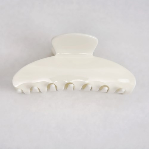 A white plastic hair clip with a curved shape and multiple teeth for holding hair.