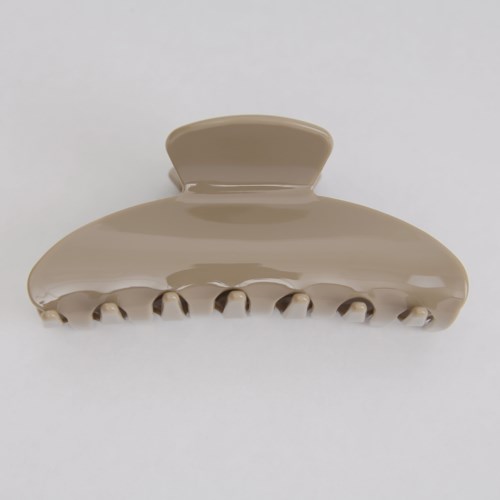 A beige hair clip with multiple teeth and a rounded top, used to hold hair back.