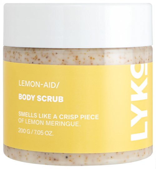 En beholder med Lemon-Aid kroppsskrubb med gul etikett, som beskriver duft og størrelse, og en hvit lokk.