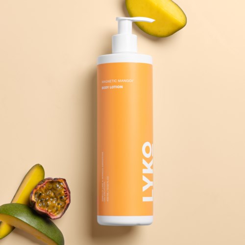 Een oranje fles met bodylotion en dispenser, omgeven door mango en passievrucht slices.