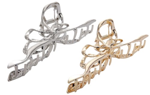Två hårspännen formade som fjärilar, ett i silver och ett i guld, med ordet 'boss' inbyggt i designen.