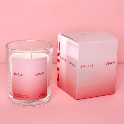 En pink og hvid pakke med duftlys i glas, mærket som duftende af drue.