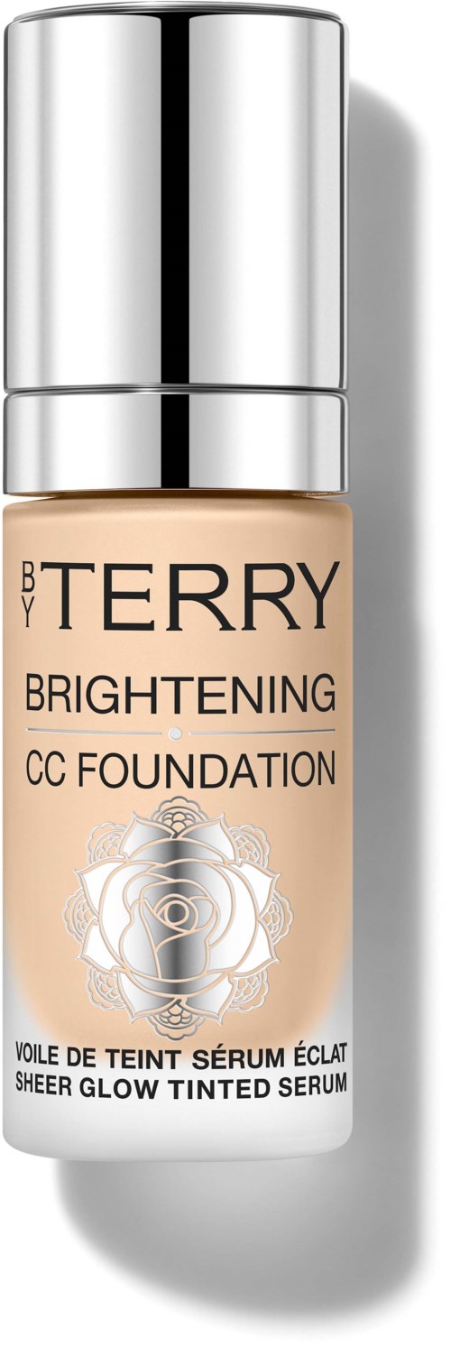 En flaske med beige flytende foundation med sølvhette, merket 'BY TERRY Brightening CC Foundation,' med roser og låsdesign.