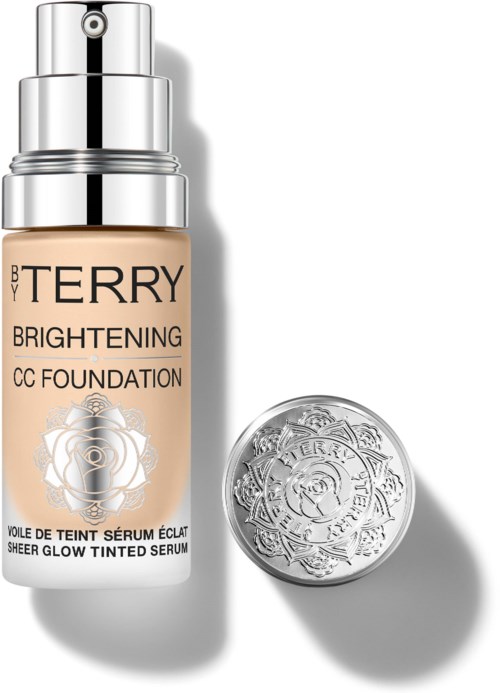 En flaske med BB Terry Brightening CC Foundation og en sølvsminke med blomsterdesign.