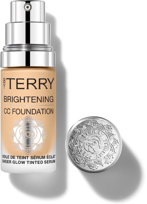 En flaske BB Terry Brightening CC Foundation med sølvhette og en rund beholder i nærheten.