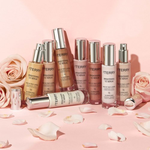 A collection of skincare bottles with roses and petals on a pink background, indicating beauty and care products.