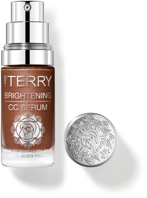 En brun flaske med BY TERRY Brightening CC Serum med sølvpumpe, og et sølvdekorativt lokke med rose-mønster.