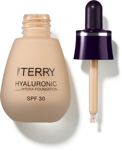 Bildet viser en foundationflaske og en dråpe med lilla hette. Foundationen er merket "BY TERRY Hyaluronic SPF 30."