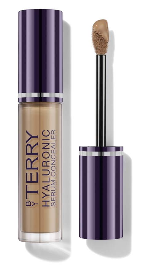 A concealer bottle with purple and silver design, label reads 'BY TERRY Hyaluronic Serum Concealer', applicator wand shown.