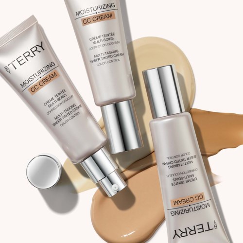 To tuber med foundation og en liten skål med beige og hvit kosmetikk, på en beige bakgrunn.