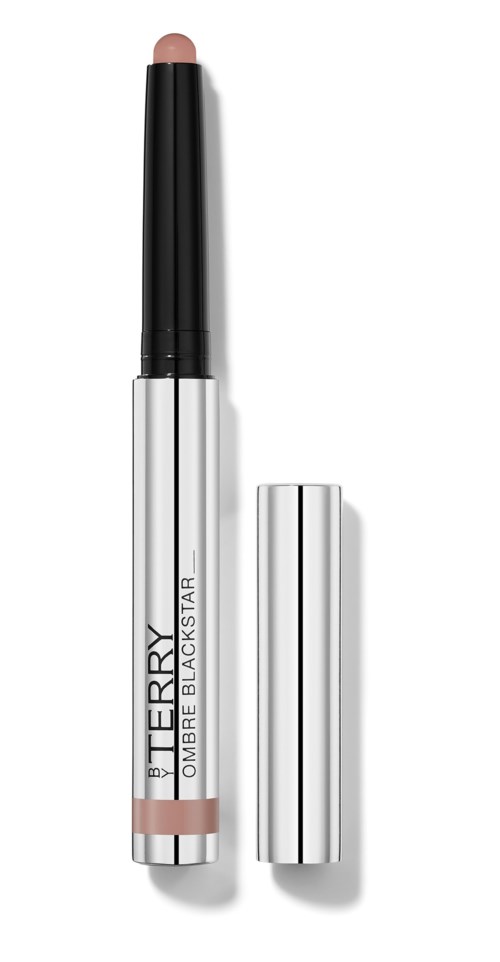 A beige makeup stick with a black cap, labeled 'BY TERRY,' lying upright with the cap off.