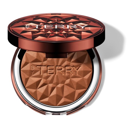 En kompakt med makeuppulver, preget med merkevaren 'BY TERRY', i en rund, dekorativ innpakning.