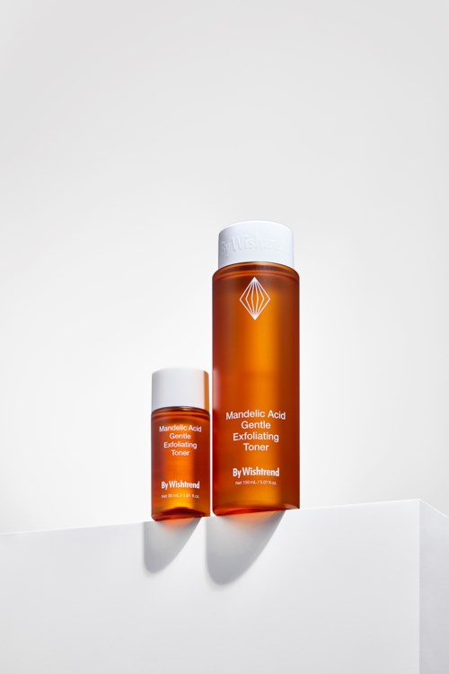 To oransje flasker med hudpleieprodukter med hvite lokk, merket som mandelic acid toner av Wishtrend, på en hvit overflate.