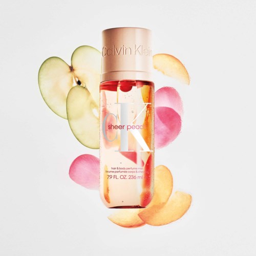 Calvin Klein Sheer Peach kroppsspray med persikoskivor och rosa, orange och gröna blomblad runt den.