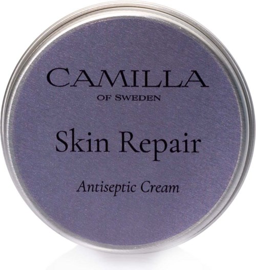 Een ronde verpakking met paarse deksel, gemarkeerd 'Camilla of Sweden Skin Repair Antiseptic Cream.'