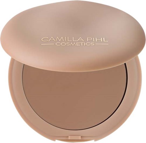 En rund sminke-kompakt med beige etui, åpnet for å vise lysebrunt pulver inni, merket Camilla Pihl Cosmetics.