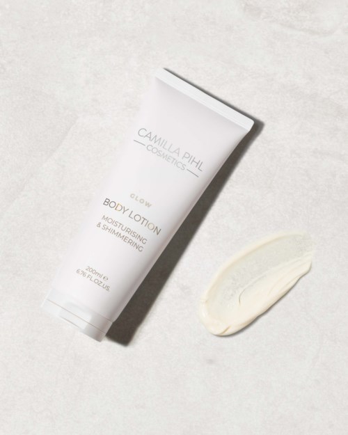 Valkoinen putkilopakkaus, jossa lukee 'Camilla Pihl Cosmetics Glow Body Lotion', ja sen vieressä on kerma.