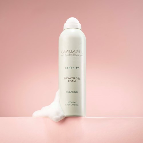 Vit flaska från Camilla Pih Cosmetics Serenity duschgört med skum som rinner ut.
