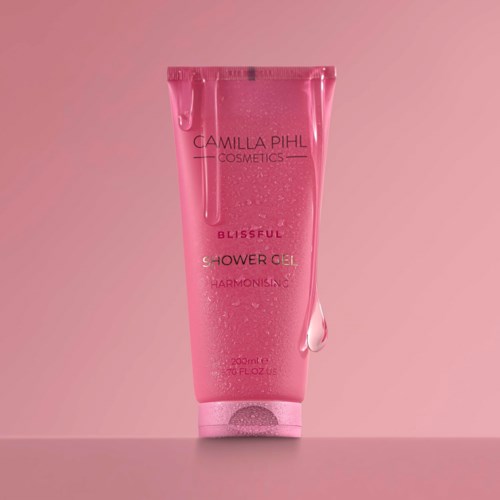 Pinkki puteli Camilla Pihl Cosmetics suihkugeeliä vaaleanpunaisella taustalla.