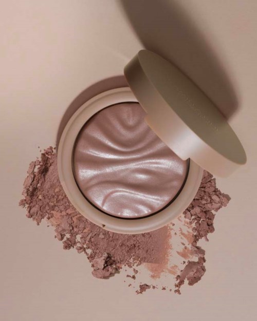 Pyöreä voidepurkki shimmer pink -meikkiä ja vähän irtopuuteria ympärillä.