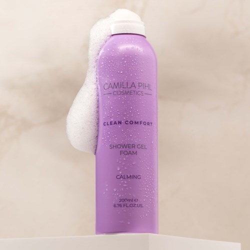 Violetti suihkugeelipullo, jonka kyljessä on vaahtoa, merkintä Camilla Pihl Cosmetics Clean Comfort Shower Gel Foam.