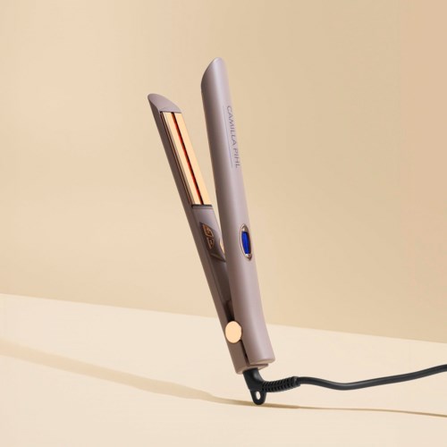 A gray hair straightener with blue and black details, resting on a beige surface.