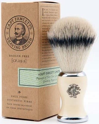 A shaving brush with a white handle and black tips, next to a brown cardboard box labeled for shaving brush.
